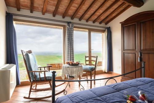 una camera da letto con tavolo, sedie e una grande finestra di Agriturismo Le Crete - Appartamenti ad Asciano