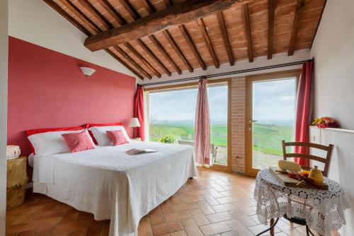 a bedroom with a bed and a large window at Agriturismo Le Crete - Appartamenti in Asciano