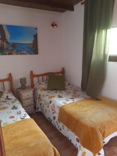 Monte de Breña的住宿－Casitas Conchi A，一间卧室设有两张床,墙上挂着一幅画