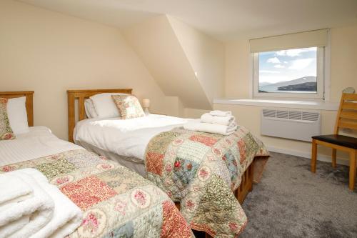 a bedroom with two beds and a window at Jetty Cottage, a self-catering cottage sitting on the jetty, with sea view in Amhuinnsuidhe