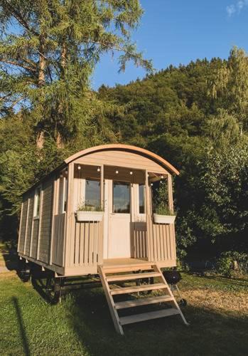 una piccola casa seduta sull'erba in un campo di Roulotte - Camping l'Eau Vive a Martelange