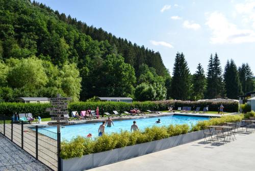 una piscina con gente en un complejo en Roulotte - Camping l'Eau Vive, en Martelange