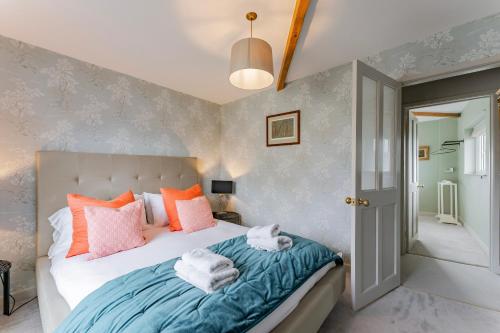 een slaapkamer met een bed met roze en oranje kussens bij The Old Concert Hall - Norfolk Cottage Agency in Holt