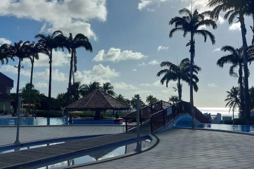 a swimming pool with palm trees and a slide at Studio "Prestige" Sainte Luce" Adult Only in Sainte-Luce