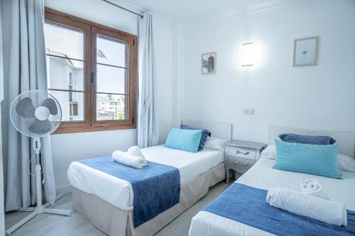 2 camas en una habitación con ventilador y ventana en CARABELA 93, en Alcudia