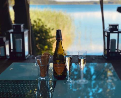 a bottle of champagne and two glasses on a table at Siedlisko Dziki Gil na Mazurach z prywatną plażą i SPA! in Ruś