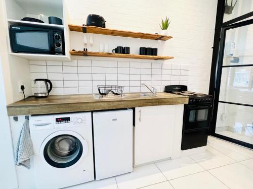 uma cozinha com uma máquina de lavar roupa e um lavatório em Industrial CHIC Apartment 113 em Joanesburgo