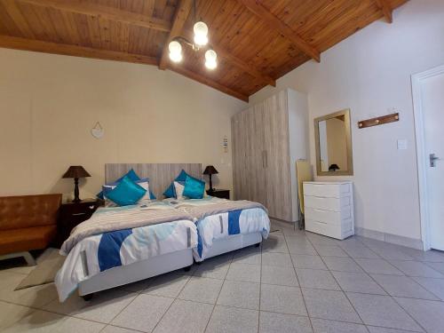 sypialnia z dużym łóżkiem z niebieskimi poduszkami w obiekcie Lyn's Self Catering w mieście Swakopmund