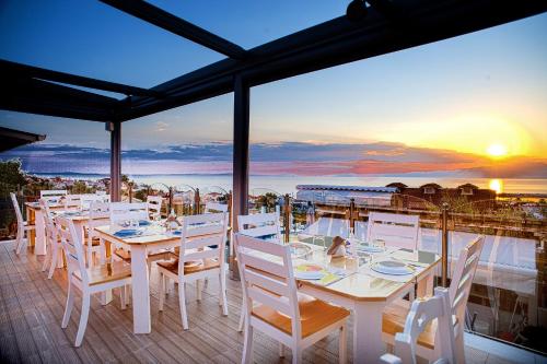 a table with white chairs and a view of the ocean at Anny Residences & Suites in Skala Kallirachis