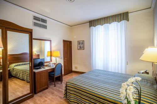 a hotel room with a bed and a desk and a mirror at Hotel Martelli in Florence