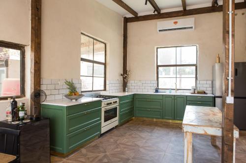 duża kuchnia z zielonymi szafkami i oknami w obiekcie Vintage high design lofts -by Bookiz w Tel Awiwie