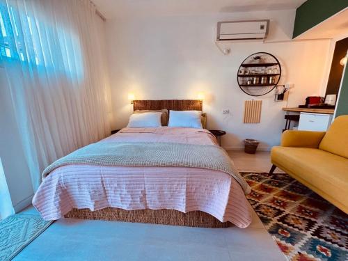 Eilat charming & cozy Studio في إيلات: غرفة نوم بسرير كبير واريكة صفراء