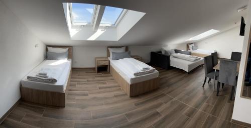 um quarto no sótão com 2 camas e um sofá em Boardinghouse MDS em Aschheim