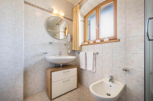 ein weißes Badezimmer mit einem Waschbecken und einem Spiegel in der Unterkunft Manuel's Edelweiss in Sexten