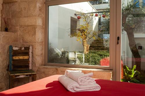 ein Bett mit Handtüchern auf einer roten Decke neben einem Fenster in der Unterkunft Trulli in corte in Alberobello