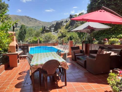 格拉納達的住宿－Cortijo La Mata，庭院配有桌椅和遮阳伞。
