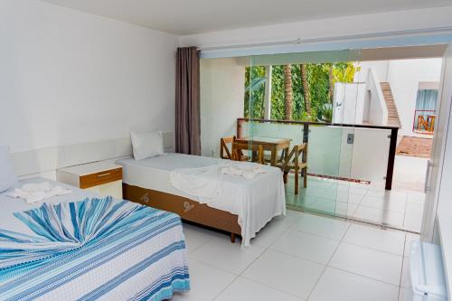 モロ・デ・サンパウロにあるBrisa do Mar Praia Hotelのベッドルーム1室(ベッド2台、テーブル付)、バルコニーが備わります。