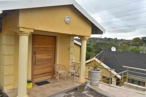 a house with a porch with chairs and a wooden door at Tranqulity In Sarnia in Pinetown