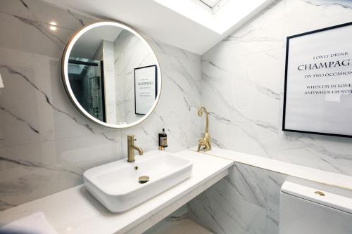 a white bathroom with a sink and a mirror at The Ferryman Townhouse in Dublin