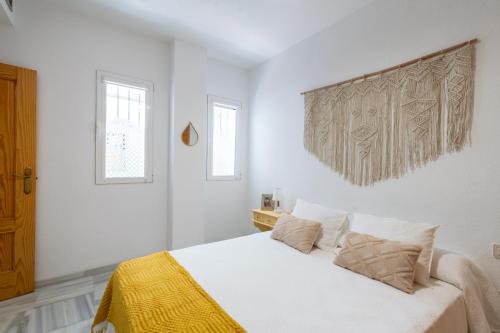 セビリアにあるApartamento con garaje, centro de Sevillaの白いベッドルーム(ベッド1台、窓2つ付)