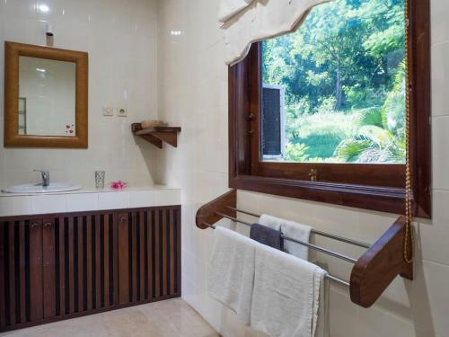 La salle de bains est pourvue d'un lavabo, d'une fenêtre et de serviettes. dans l'établissement Villa 7, Secret Garden, Kerandangan, near Senggigi, à Mataram