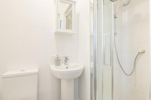 een witte badkamer met een wastafel en een douche bij Stylish Studio 4 with Kitchenette by CB Stays no minimum stays in Cambridge