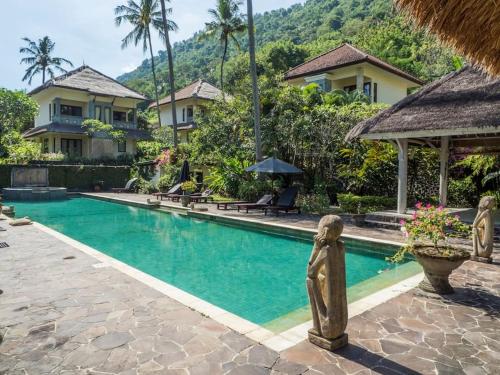 a swimming pool with a statue in front of a house at Villa 7, Secret Garden, Kerandangan, near Senggigi in Mataram