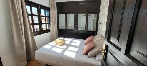 a bedroom with a white bed with pink pillows at Hotel Ecolife Tenerife in San Miguel de Abona