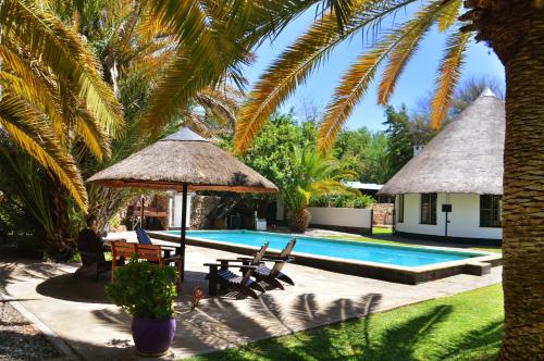 a resort with a swimming pool and palm trees at Central Hotel Omaruru in Omaruru