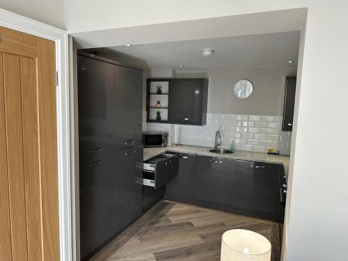 a large kitchen with black cabinets and a sink at Beach Pad - ground floor - pet friendly in Cleveleys