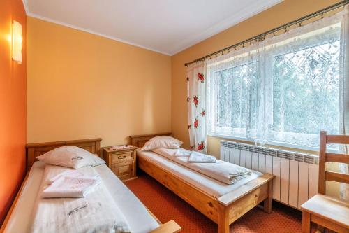 two beds in a room with a window at Willa Paula in Ząb