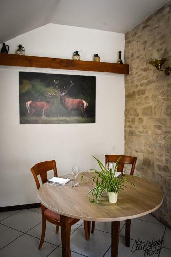 a wooden table with chairs and a painting of deer at Hostellerie Du Chateau in Châteauneuf