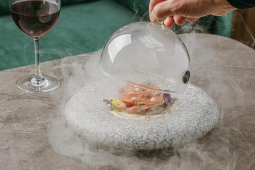 a person holding a bowl of food in a glass of wine at Catalonia Barcelona Plaza in Barcelona