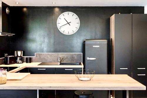 a kitchen with a refrigerator and a clock on the wall at LE PTIT LOCMARIA - Calme - Wifi - Proche Centre ville in Quimper