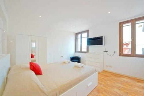 a white bedroom with a large bed with red pillows at On the roofs to Piazza San Marco - Venezia in Venice