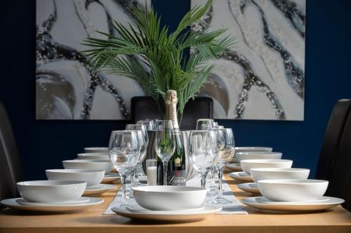 una mesa con platos blancos y copas de vino. en Debenham Lodge Margate en Kent