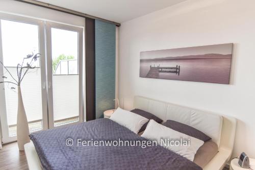 een slaapkamer met een bed en een groot raam bij Deichresidenz Stein in Stein