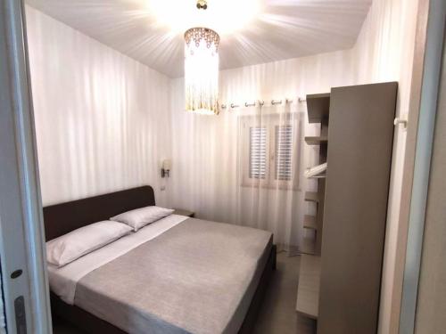 een kleine slaapkamer met een bed en een kroonluchter bij Casa Vacanze Onda Azzurra (Deluxe) in Peschici