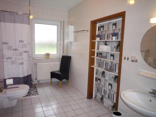 ein Badezimmer mit einem Waschbecken, einem WC und einem Stuhl in der Unterkunft Ferienzimmer Alte Kämpe in Heede