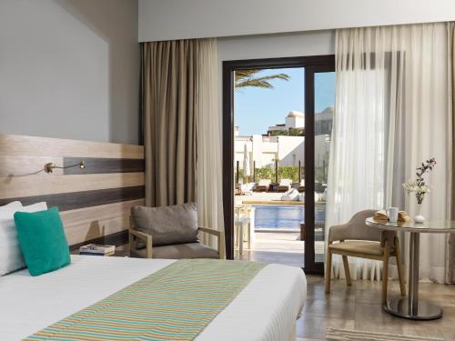 a hotel room with a bed and a table and a patio at Ancient Sands Golf Resort and Residences in Hurghada