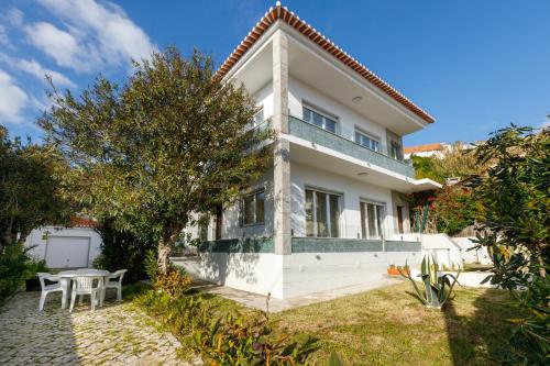 a white house with a table and chairs at Villas Boas House Caparica in Costa da Caparica