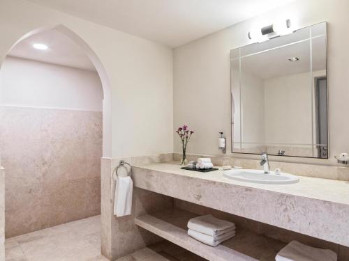 a bathroom with a sink and a mirror at Fanar Hotel & Residences in Salalah