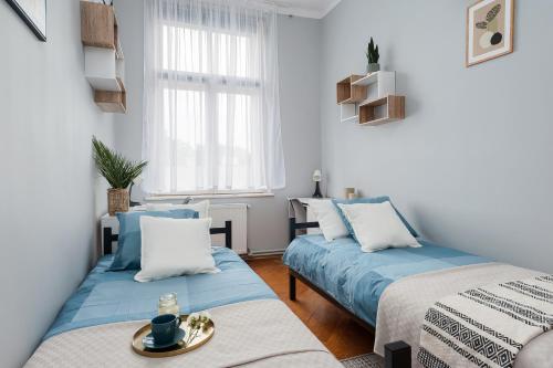 two beds in a small room with blue sheets at Wielopole Homes by LoftAffair in Krakow