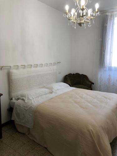 ein weißes Schlafzimmer mit einem großen Bett und einem Kronleuchter in der Unterkunft IL SICOMORO in Sansepolcro