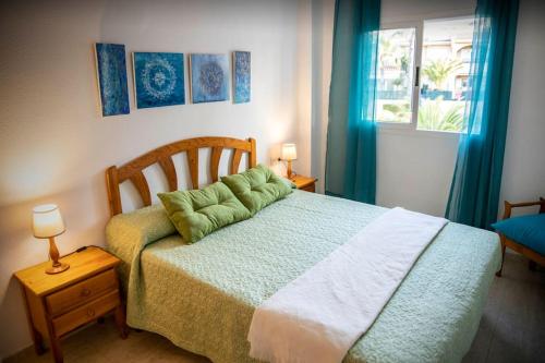 Un dormitorio con una cama con almohadas verdes. en Disfruta de la playa y piscina, acogedora casa en Santa Pola
