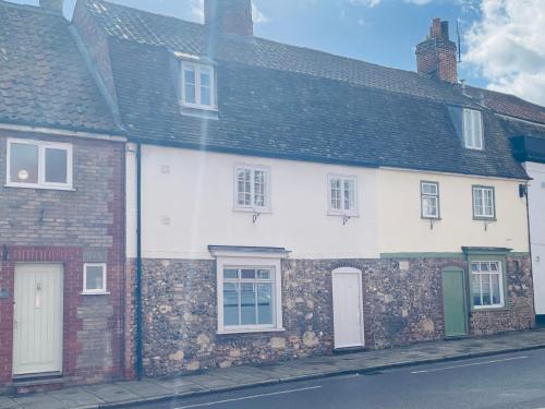 a white building on the side of a street at Abbey Gardens Cottage in Bury Saint Edmunds