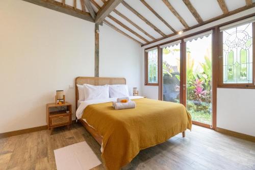 een slaapkamer met een bed met een gele deken bij Singgah di Ubud 1 in Ubud