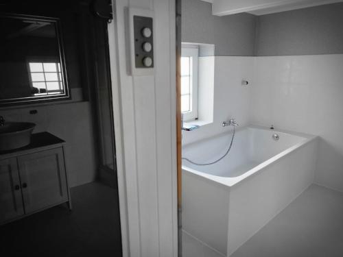 a white bathroom with a tub and a sink at Urlaub im blauen Haus in Sehestedt