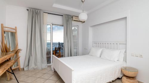 a bedroom with a white bed and a balcony at Sea Bliss Adults Only in Parga