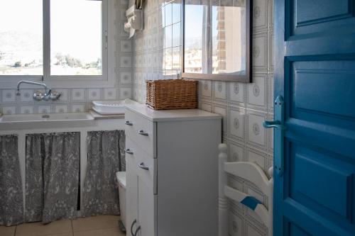 baño con lavabo y aseo y puerta azul en Primera Línea de Playa, en Algarrobo Costa